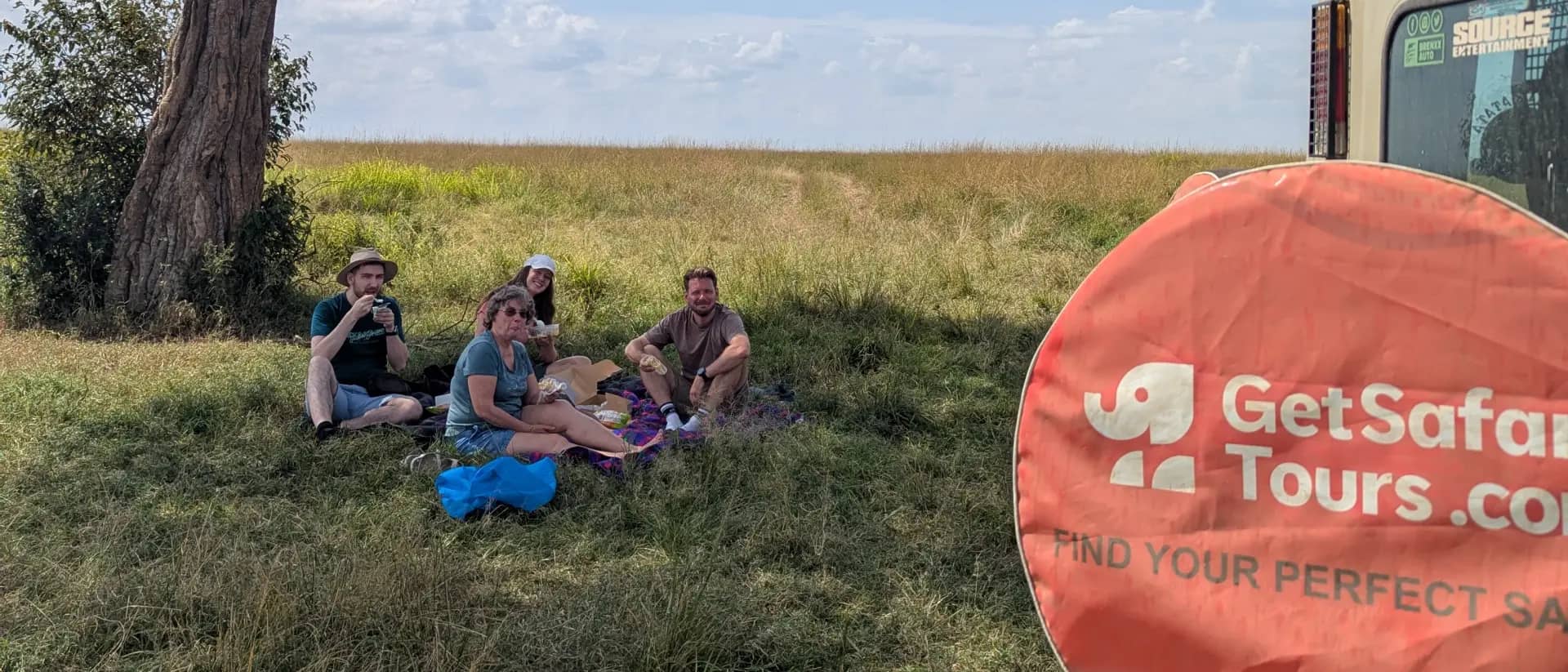 Karlis with travellers having a savanna picnic next to the branded GetSafariTours vehicle